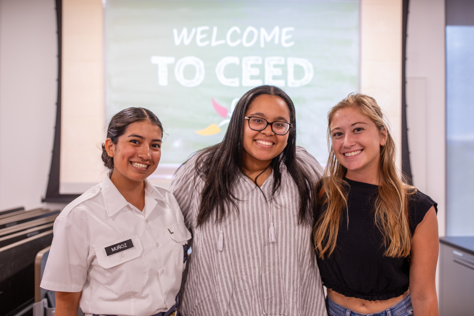 Three people standing in front of a welcome to CEED sign.
